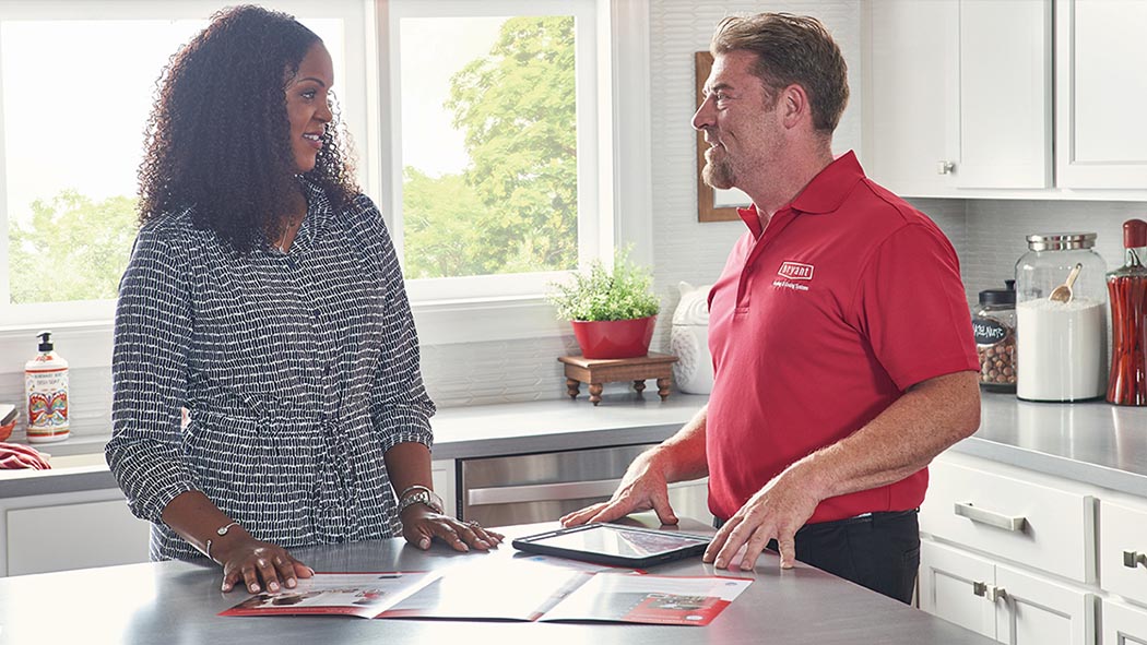 A Bryant dealer explains annual HVAC maintenance plans with a woman